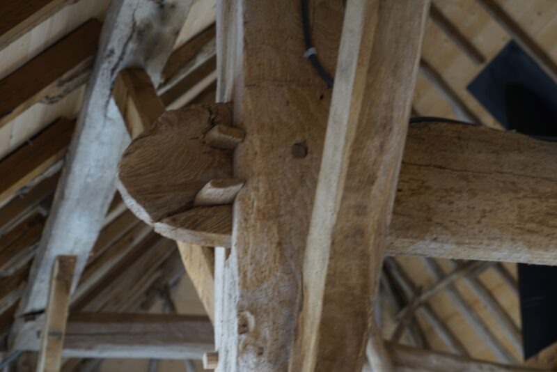 Close-up van een traditionele pen-en-gatverbinding met houten pennen in de robuuste eikenhouten draagconstructie van een gerenoveerd pand.