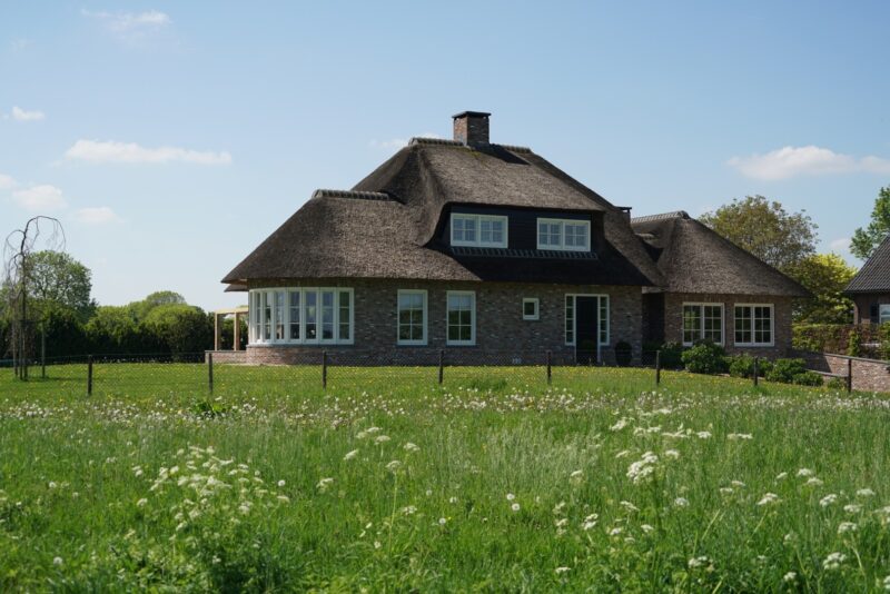Ruime nieuwbouwwoning met landelijke architectuur, gekenmerkt door een forse rieten kap met zwarte dakkapel en een glazen uitbouw, in het buitengebied van Beers.