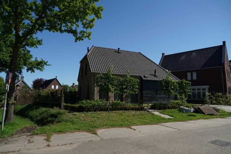 Vrijstaande woning gebouwd door Claassen Bouw, met een opvallende combinatie van een traditionele bakstenen gevel en een strakke zwarte houten aanbouw onder een donker pannendak.